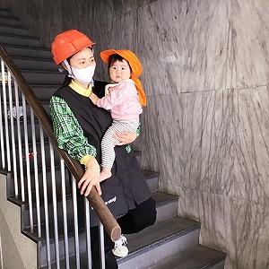 園児を抱えて屋外へ避難する保育士