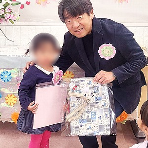 プレゼントの色紙も持つ卒園児と園長先生