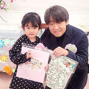 プレゼントの色紙も持つ卒園児と園長先生