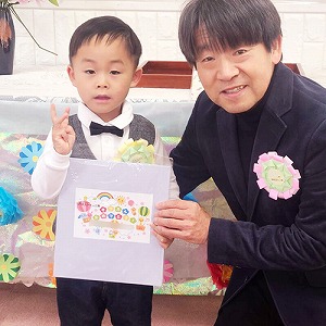 プレゼントの色紙も持つ卒園児と園長先生