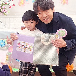 プレゼントの色紙も持つ卒園児と園長先生