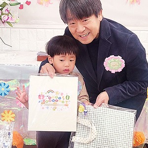 プレゼントの色紙も持つ卒園児と園長先生