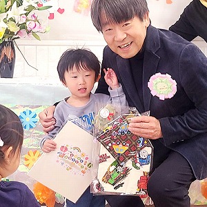 プレゼントの色紙も持つ卒園児と園長先生