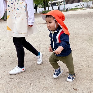 保育士と一緒に公園を走る子ども