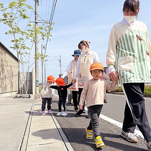 保育士と手を繋いでお散歩にでかける園児たち