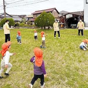 公園でシャボン玉で遊ぶ子どもたちと保育士たち