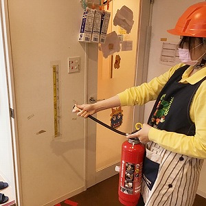 避難訓練で消火器を持つ保育士