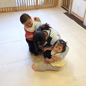 避難訓練で身を低くする保育士と子どもたち