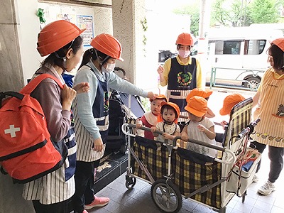 子どもたちを避難カートに乗せて避難する保育士たち