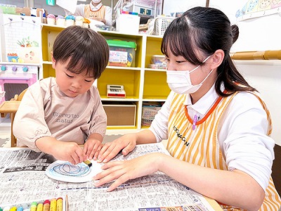 子どもの制作活動を見守る保育士
