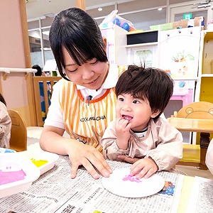 保育士と一緒に制作をする子ども