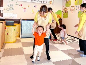 先生と手を繋いで笑顔で体を動かす子どもたち