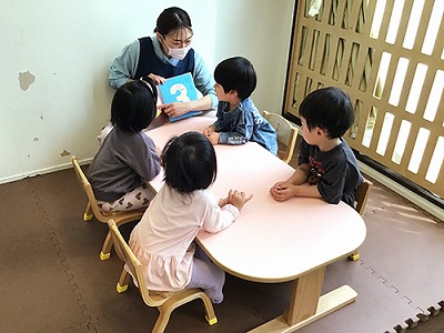 子どもたちに絵本を読み聞かせる保育士