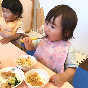 大きな口を開けて給食を食べる子ども