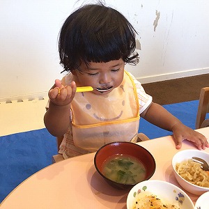 スプーンをじょうずに使って給食を食べる子ども