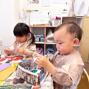 真剣な表情で折り紙をちぎる子どもたち
