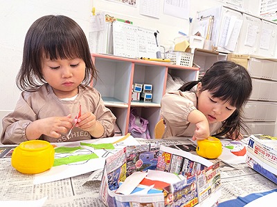 真剣な表情で、ちぎった折り紙を貼る子どもたち