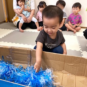 大きな箱の中にビニールテープや飾りで天の川を作る子ども