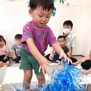 大きな箱の中にビニールテープや飾りで天の川を作る子ども