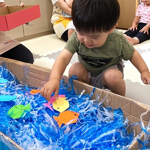 大きな箱の中にビニールテープや飾りで天の川を作る子ども