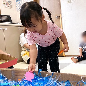 大きな箱の中にビニールテープや飾りで天の川を作る子ども