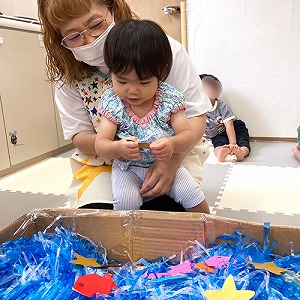 大きな箱の中にビニールテープや飾りで天の川を作る子ども