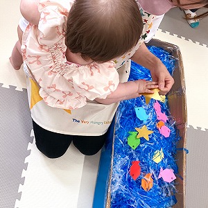 大きな箱の中にビニールテープや飾りで天の川を作る子ども