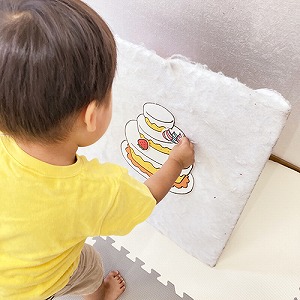 バースデーケーキのパネルに飾り付けをする子ども