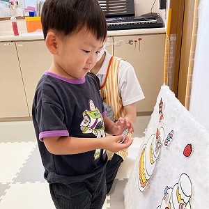 バースデーケーキのパネルに飾り付けをする子ども