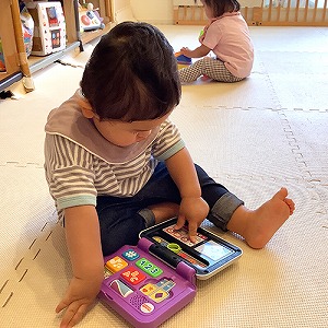 おもちゃを指先で押して遊ぶ子ども