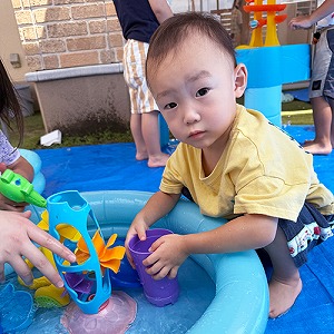 プールの中の玩具で水遊びを楽しむ子ども