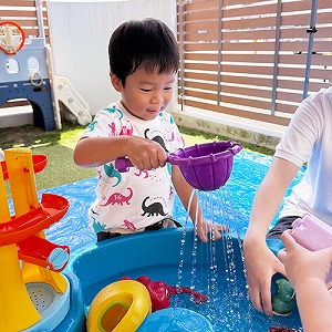 玩具を使って水遊びをする子ども