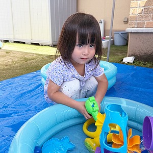 プールの中の玩具で水遊びをする子ども