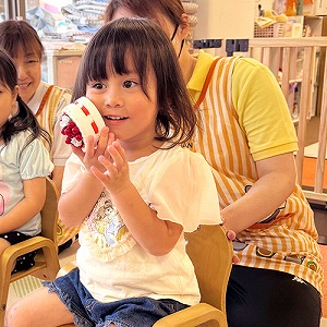 誕生日ケーキのおもちゃを持って喜ぶ子ども