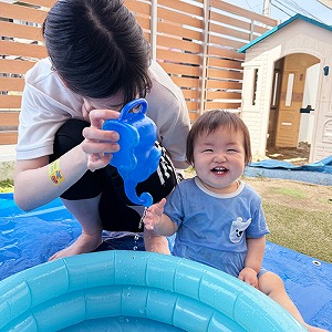 水に触れて笑顔の子どもと保育士