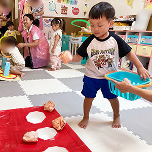 真剣な表情で夏まつりのたこ焼き投げをする子ども