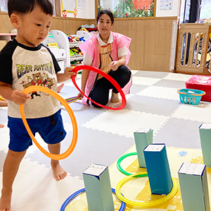先生に見守られながら輪投げをする子ども