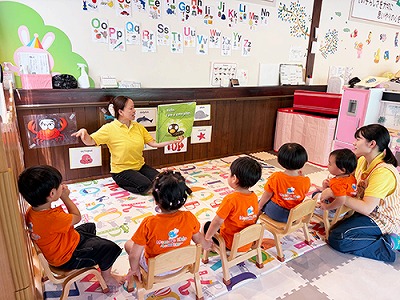 子どもたちに英語で絵本の読み聞かせをする先生