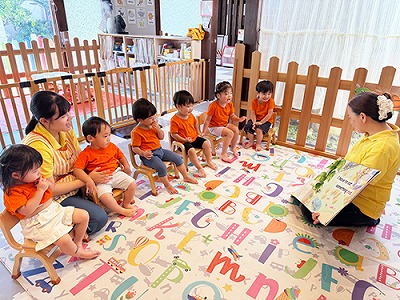 先生による英語の絵本の読み聞かせを聞く子どもたち