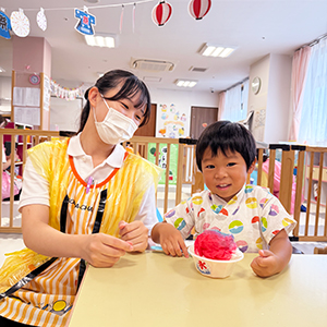 かき氷を作って微笑む子どもと保育士
