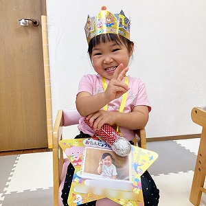 誕生日の王冠を被りピースサインをする子ども