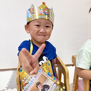 誕生日の王冠を被りピースサインをする子ども