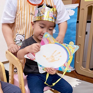誕生日の王冠を被り手形入りのカードをみつめる子ども