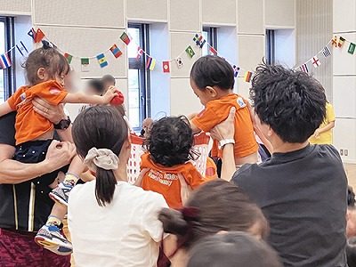 保護者に抱えられながら玉入れをする子どもたち