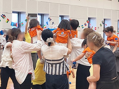 保護者に抱えられながら玉入れをする子どもたち