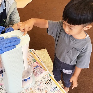 かき氷器のボタンを押す子ども