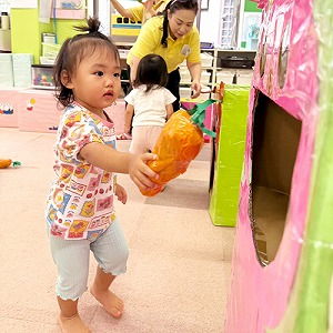 にんじんを箱でできた大きなお口に入れる子ども