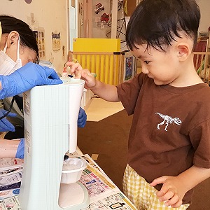 かき氷器のボタンを押す子ども