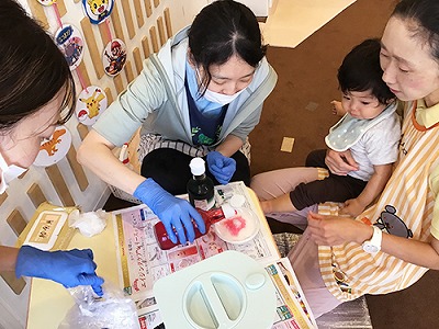 子どもたちにみつめられながらかき氷にシロップをかける先生