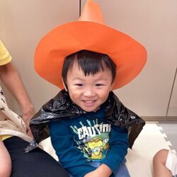 黒いマントを身に着け魔女の帽子を被る子ども